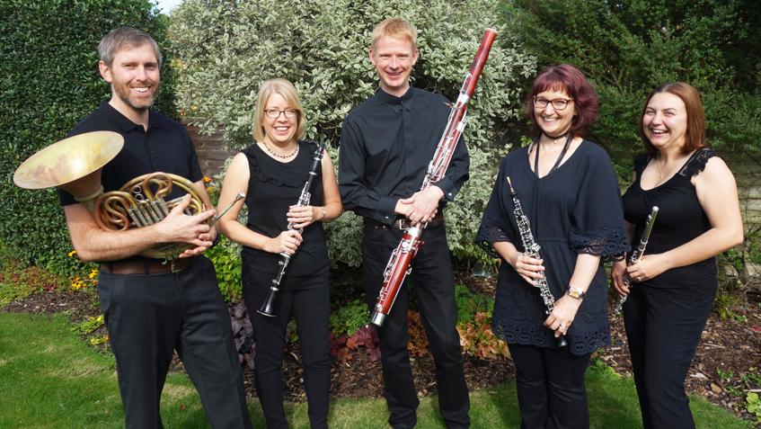 The Whiteknights Ensemble, standing in a garden with their instruments.